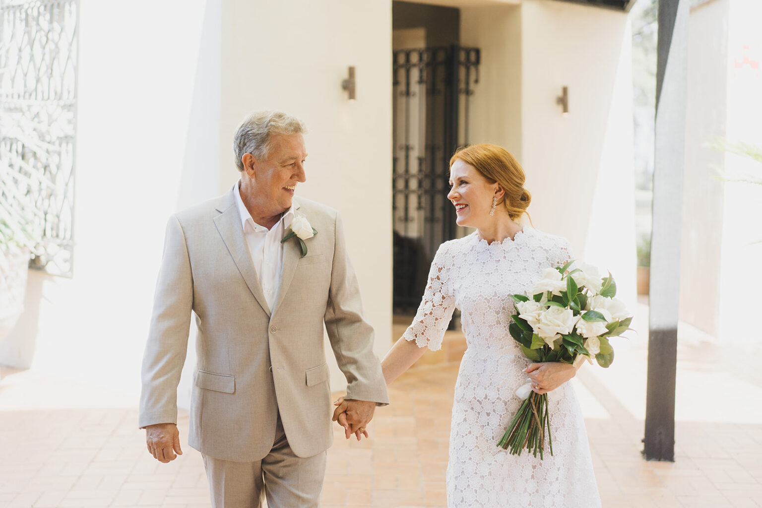 Couple smiling as they walk through a sunlit corridor at Tower Lodge