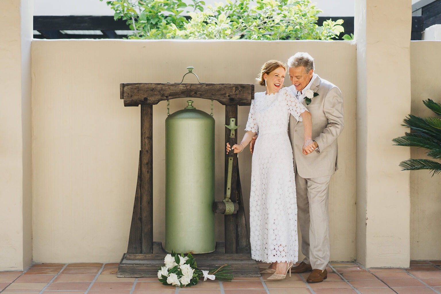 Couple beside an antique bell in a Tower Lodge courtyard