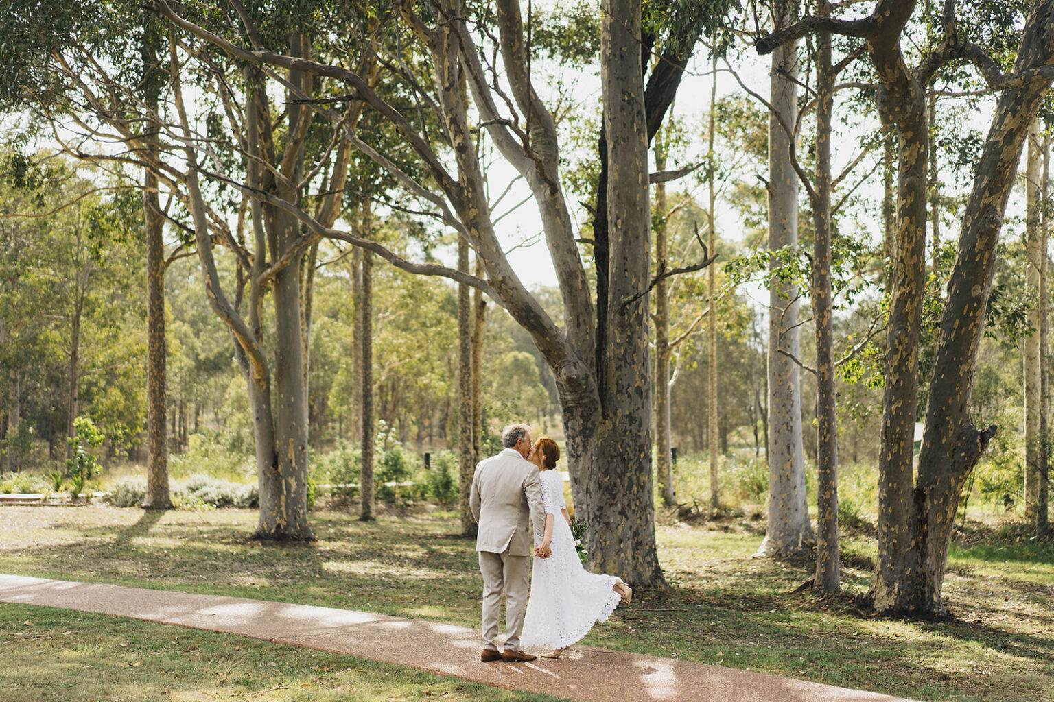 Couple embracing beneath gum trees at Tower Lodge