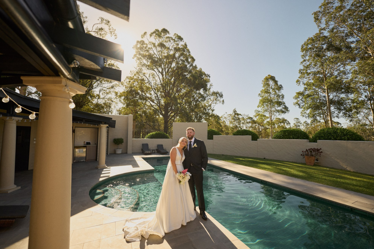 Couple standing by the pool at sunset, Tower Lodge