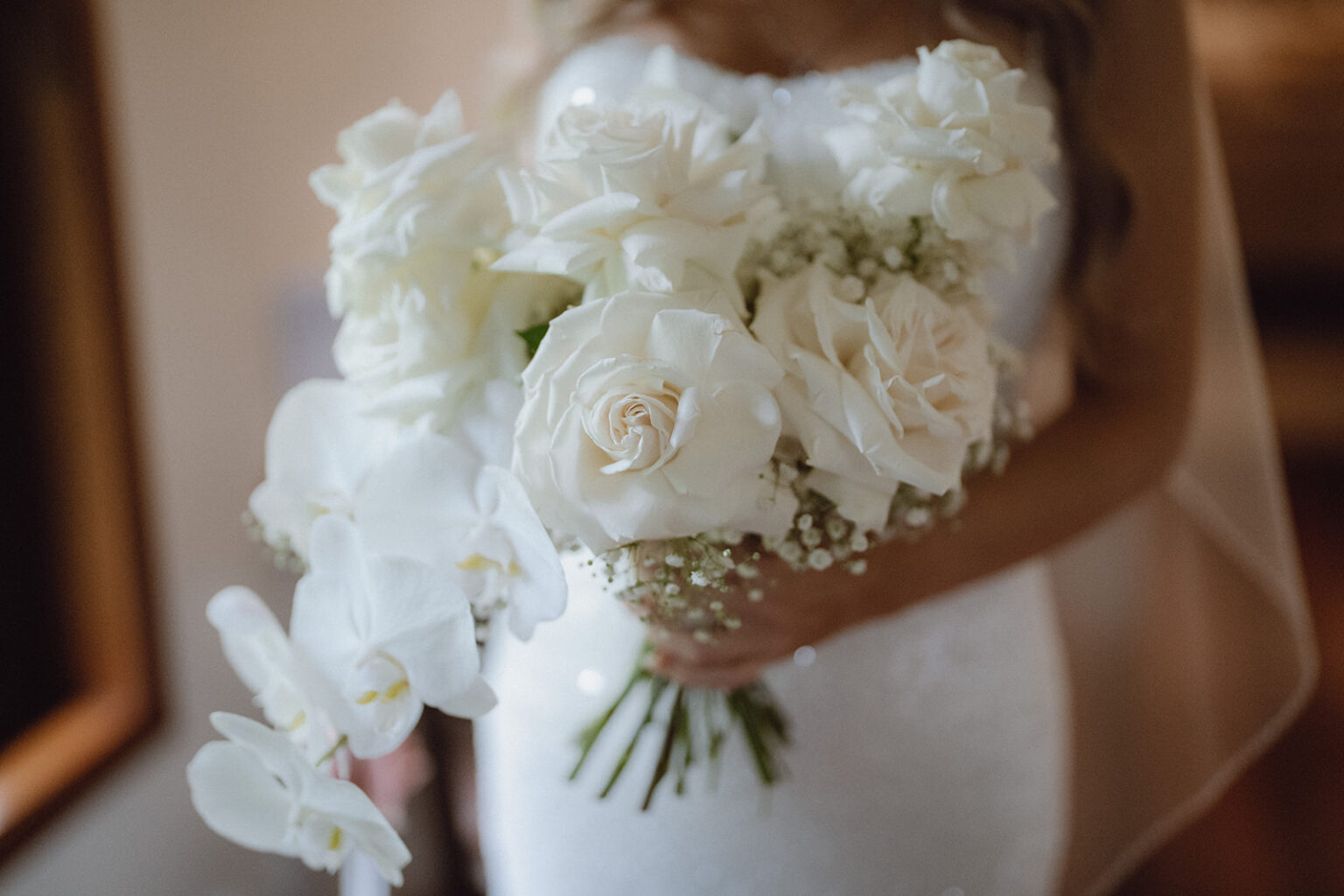 Bride holding a bouquet of white roses and orchids