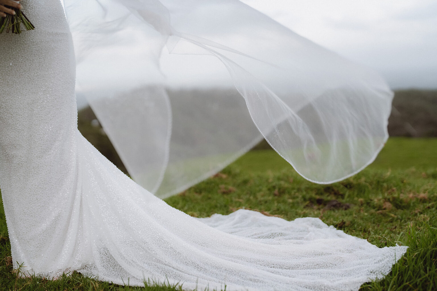 Bride's veil and train blowing across the grass