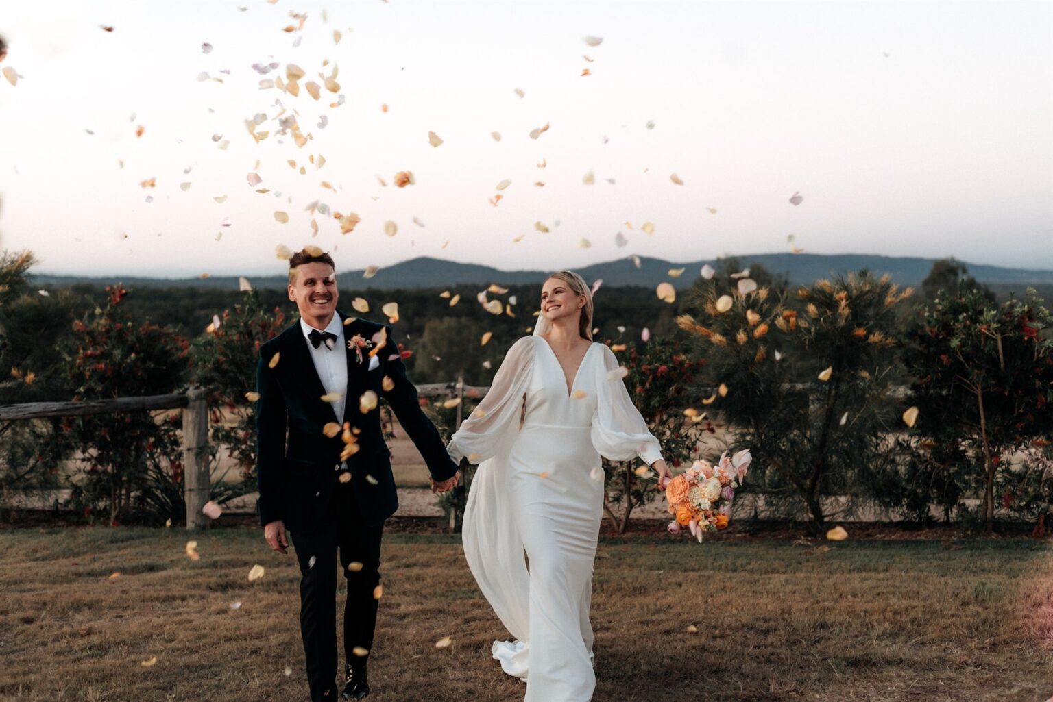 Couple walking through falling petals with valley views at Spicers Hidden Vale