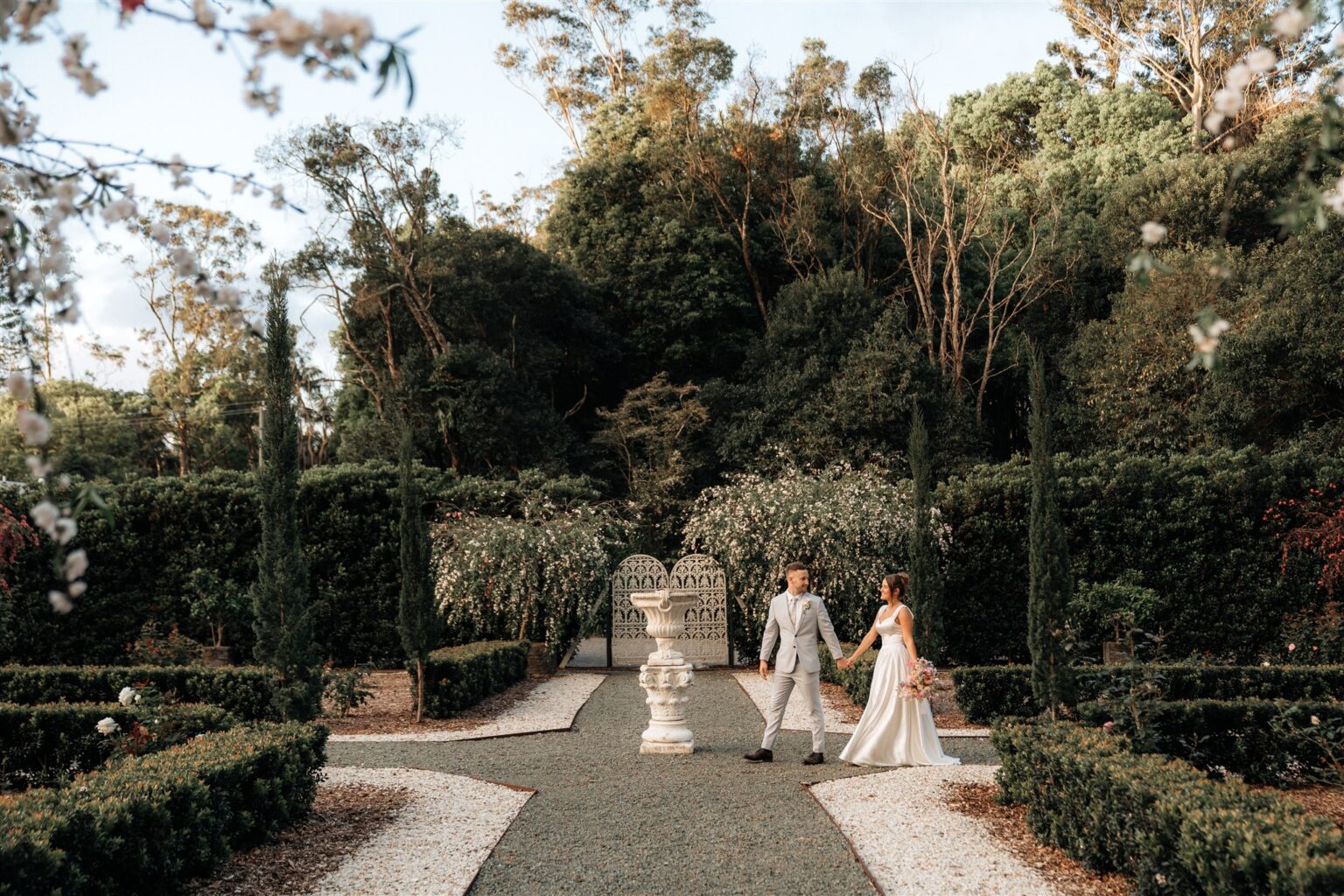 Couple walking hand in hand through the French Garden at Wynmère Estate