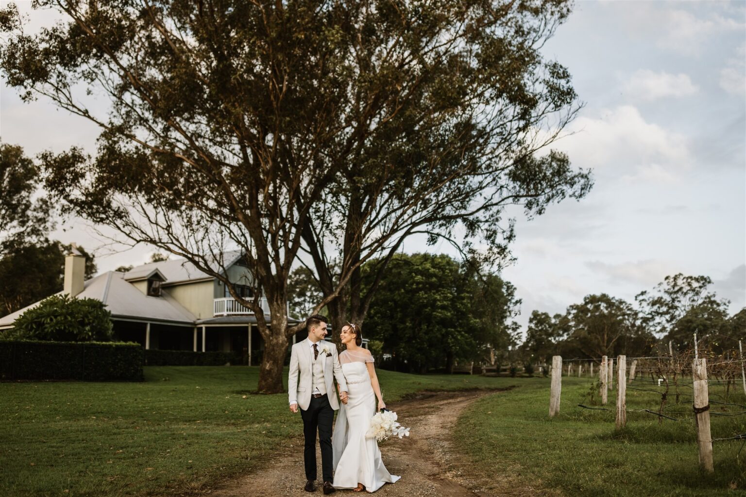 Couple on the vineyard path with the homestead behind
