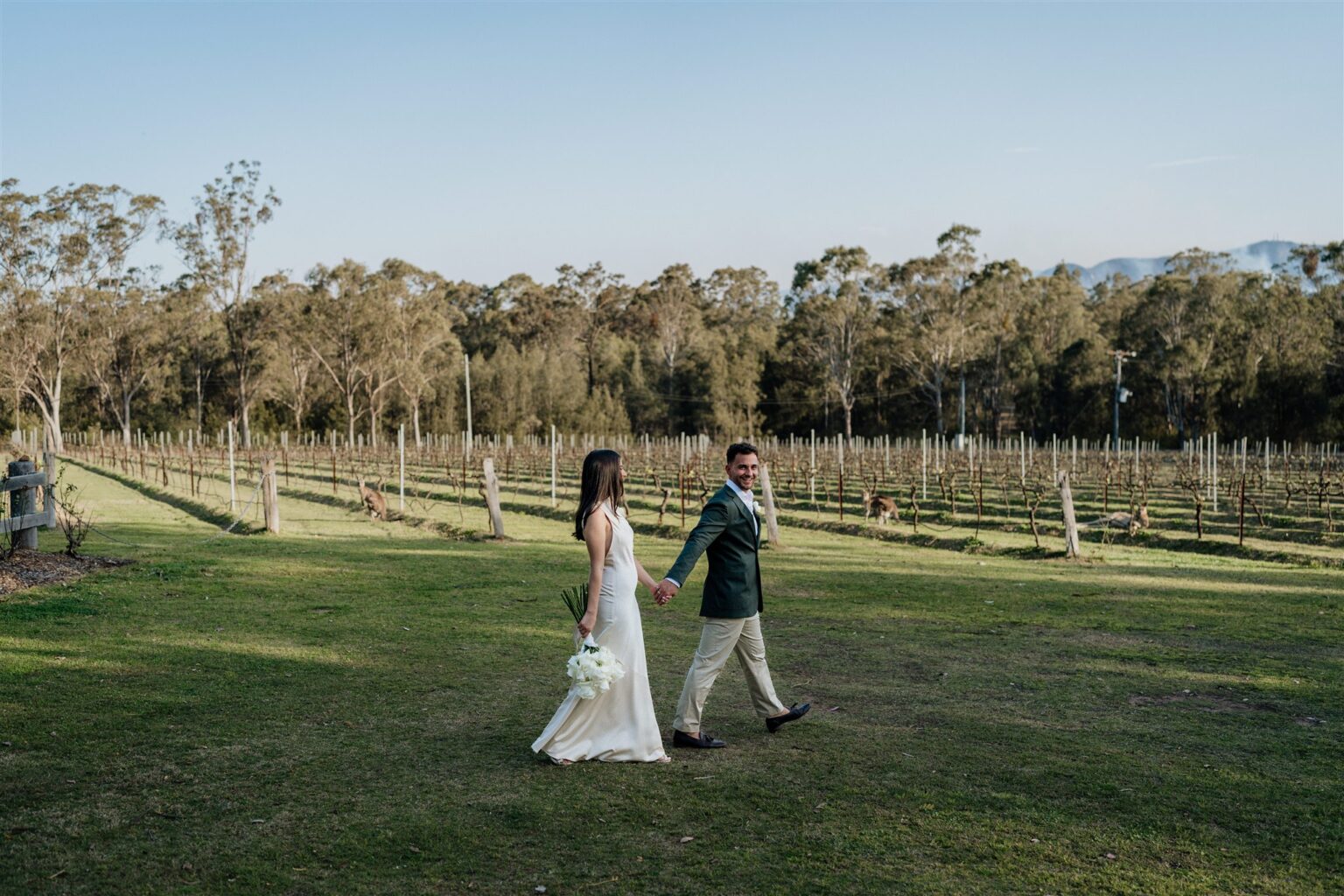 Couple walking across the lawn beside the vineyard, Hunter Valley
