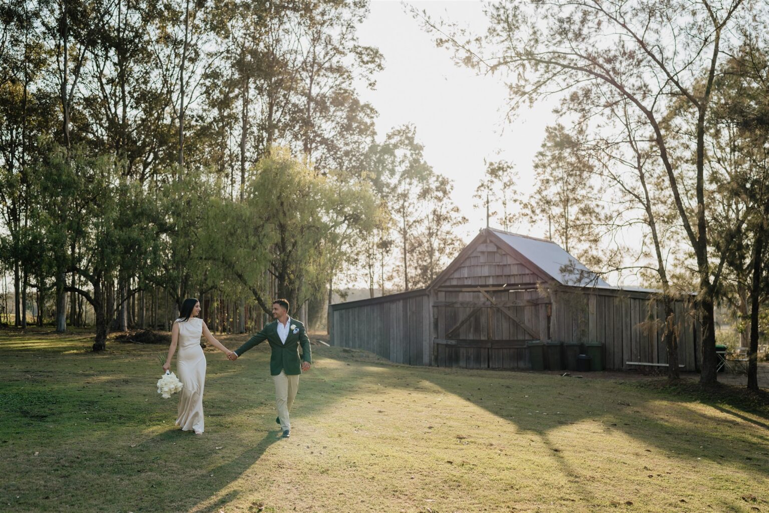Couple walking hand in hand toward the old timber barn