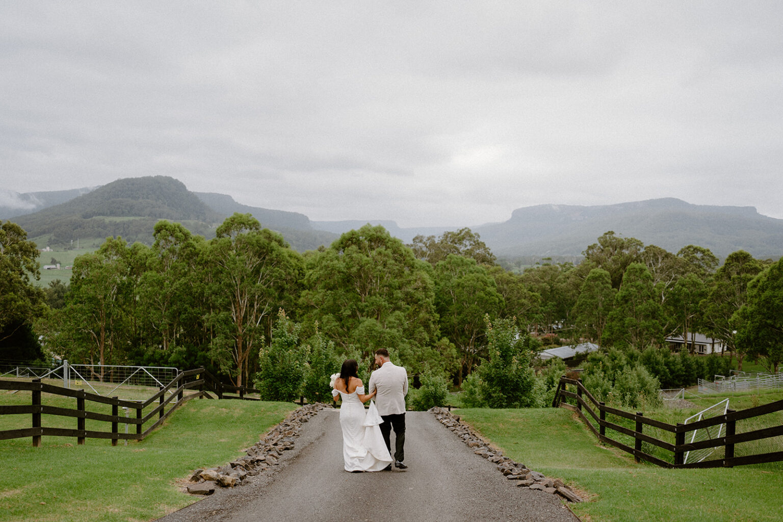 Couple walking down the fenced driveway toward the escarpment