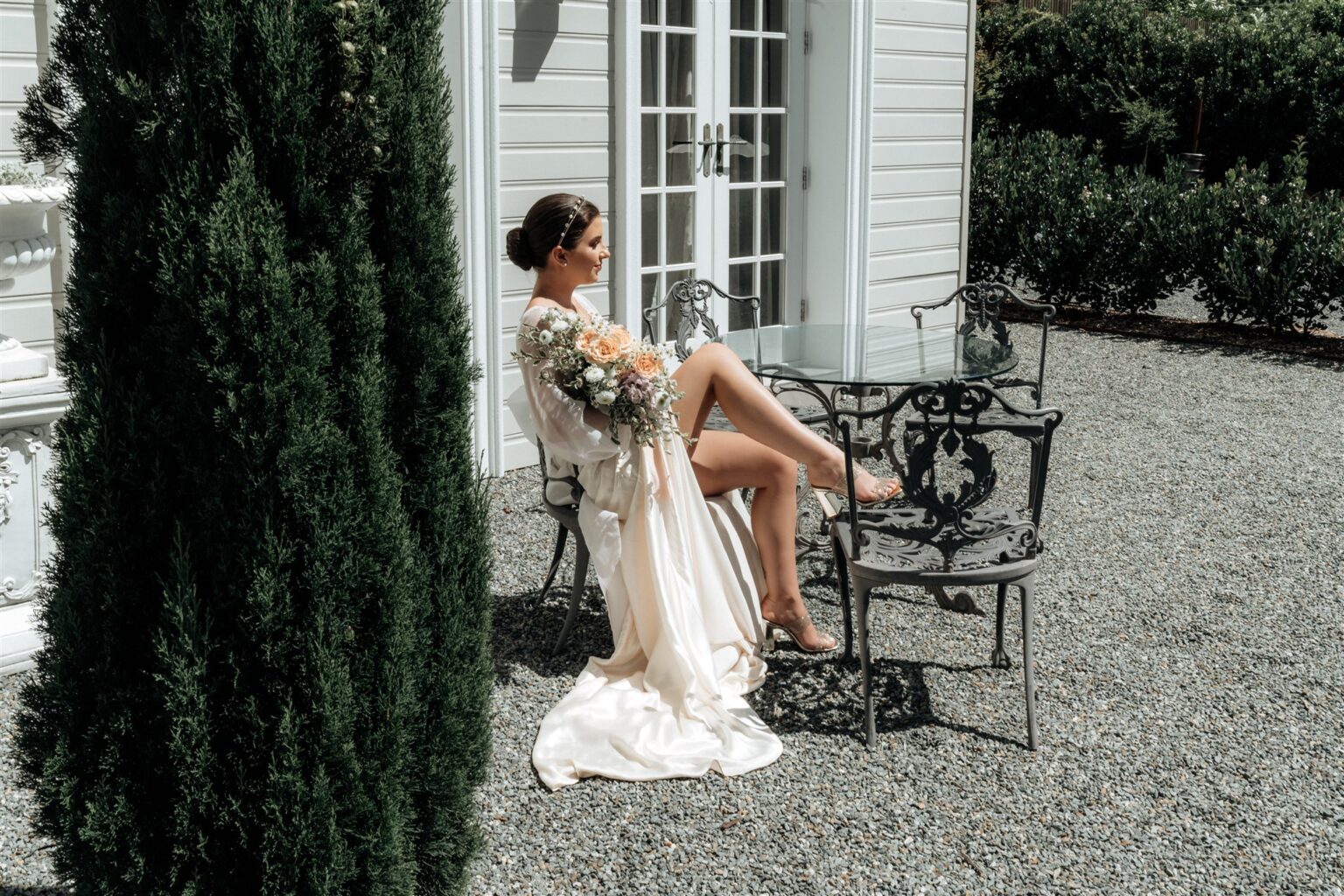 Bride seated in the courtyard beside the manor at Wynmère Estate