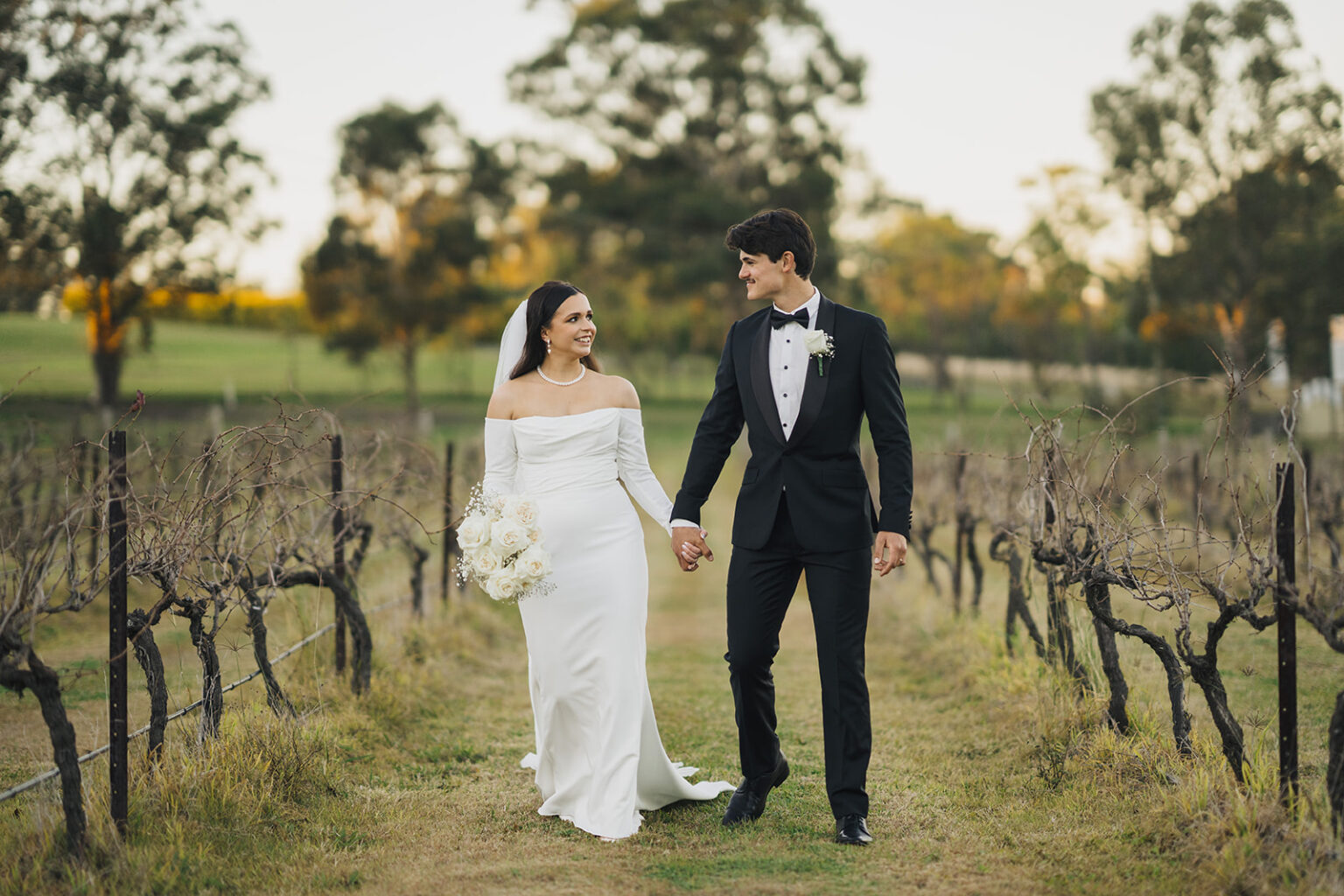 Bride and groom walking through the vineyard rows