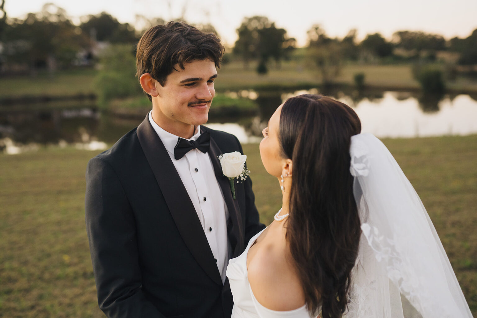 Couple smiling at each other beside the dam at sunset