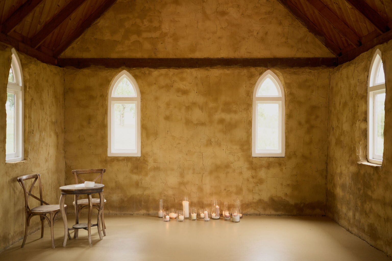 Candlelit chapel interior with arched windows at Peppers Creek