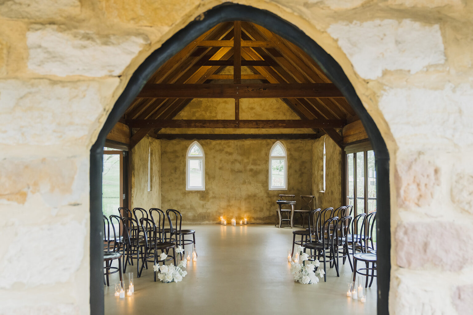 View through the chapel's stone arch to the candlelit aisle