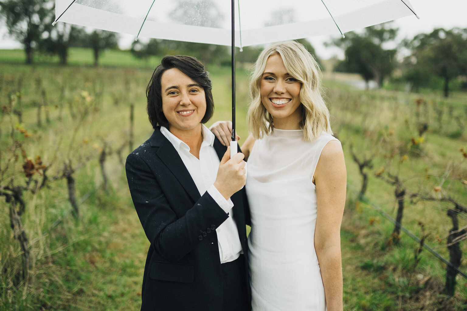 Couple sharing an umbrella among the vines