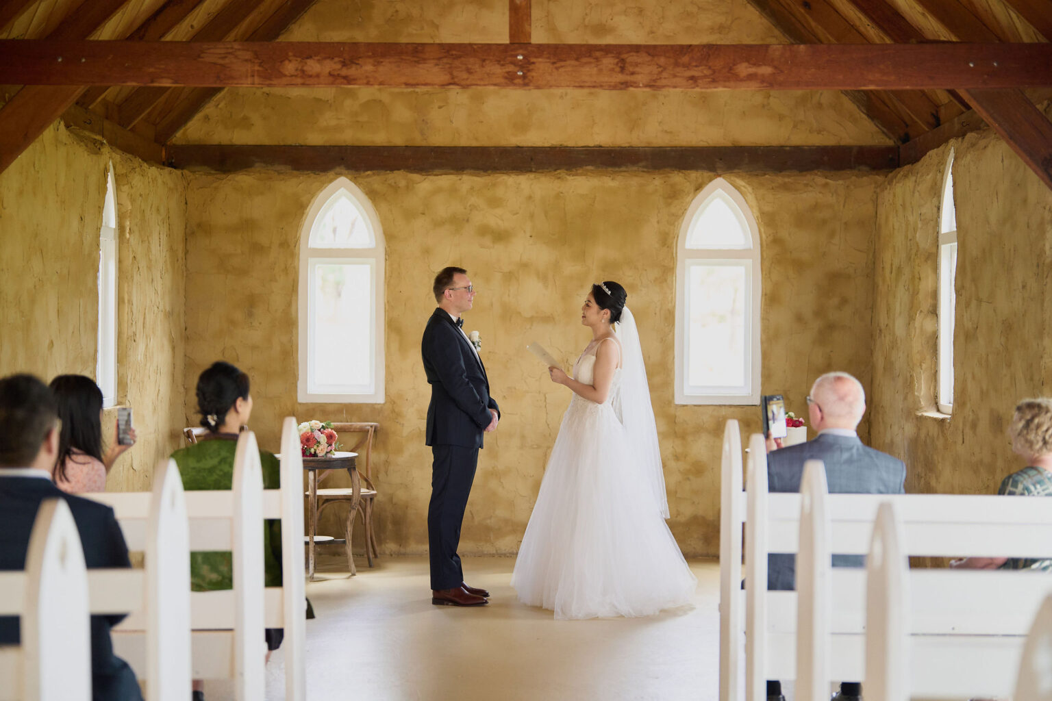 Couple exchanging vows before guests in the chapel