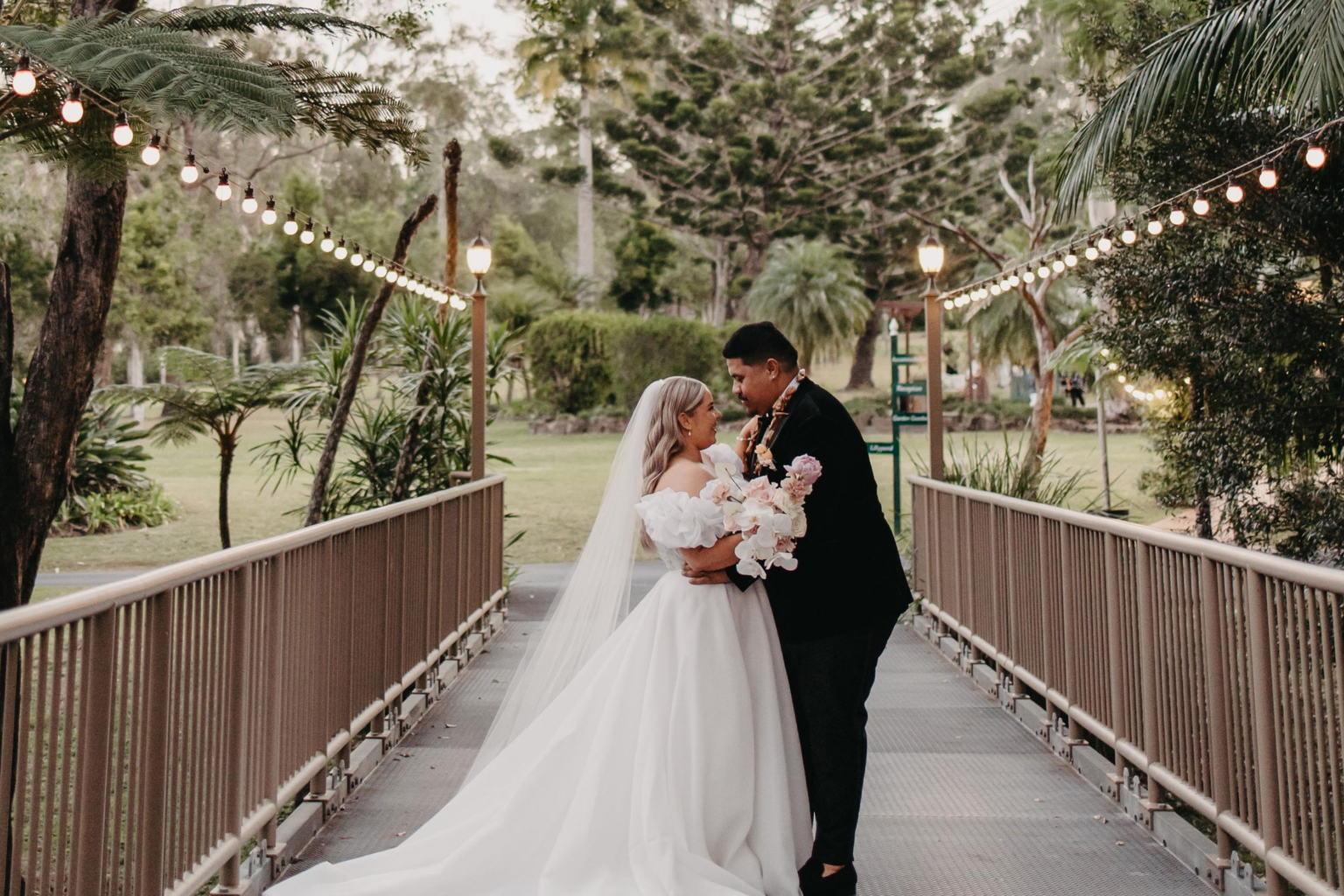 Couple embracing on the footbridge under festoon lights