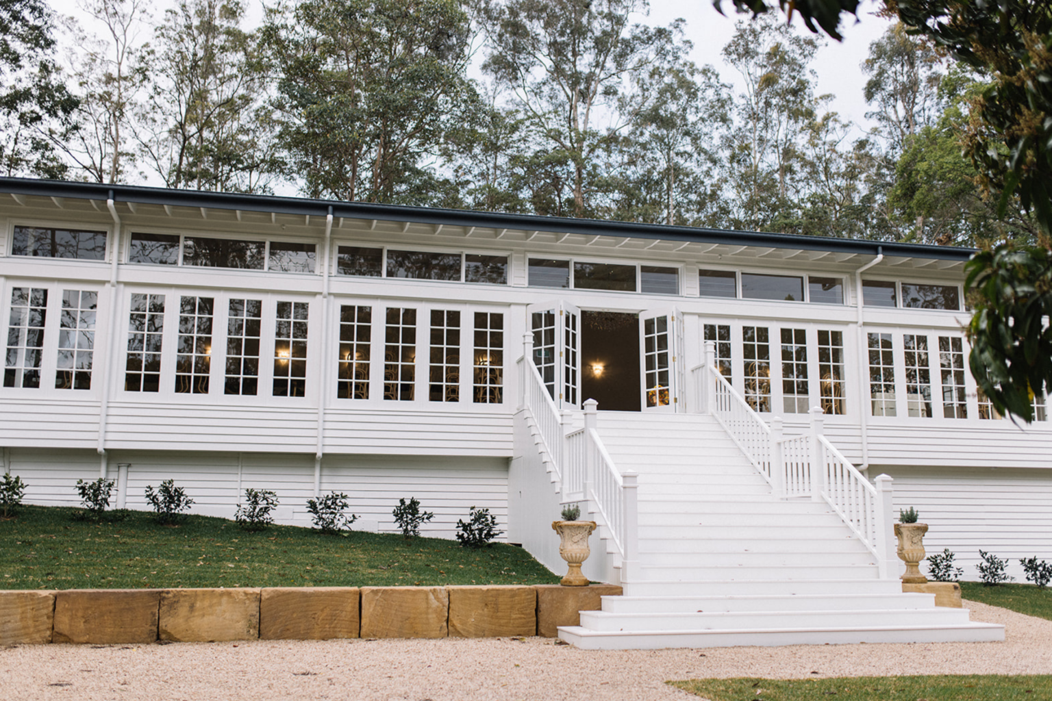 White weatherboard pavilion and grand staircase at Kwila Lodge