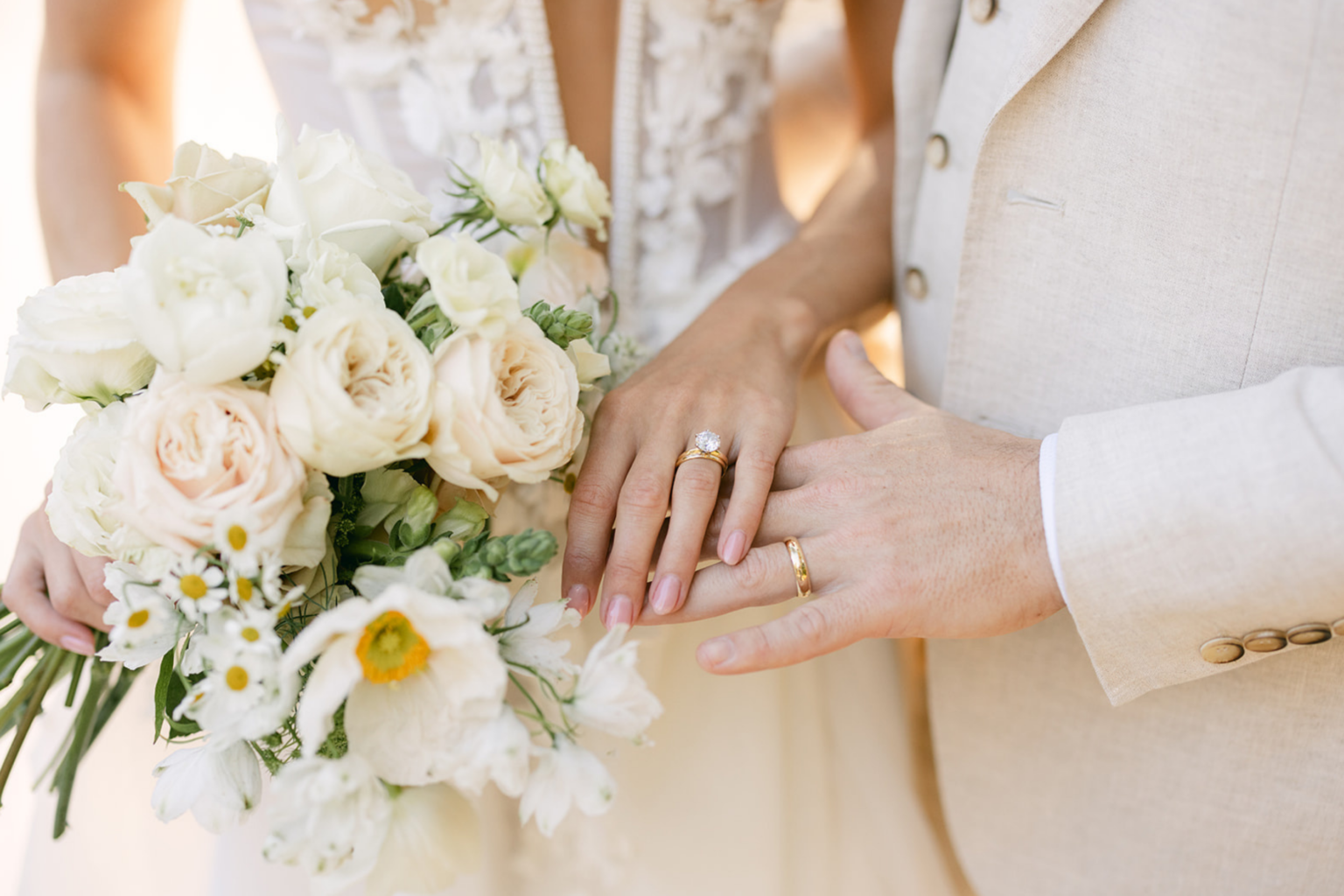 Close-up of the couple's hands and rings with the bouquet