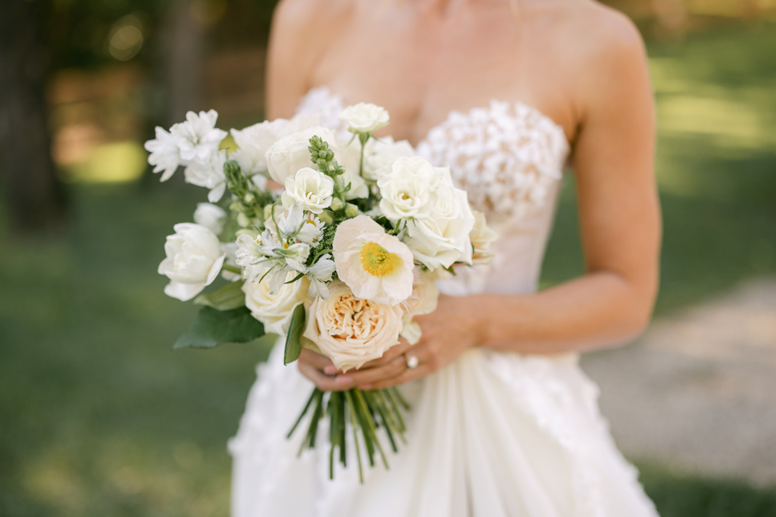 Bride holding a bouquet of white roses and ranunculus
