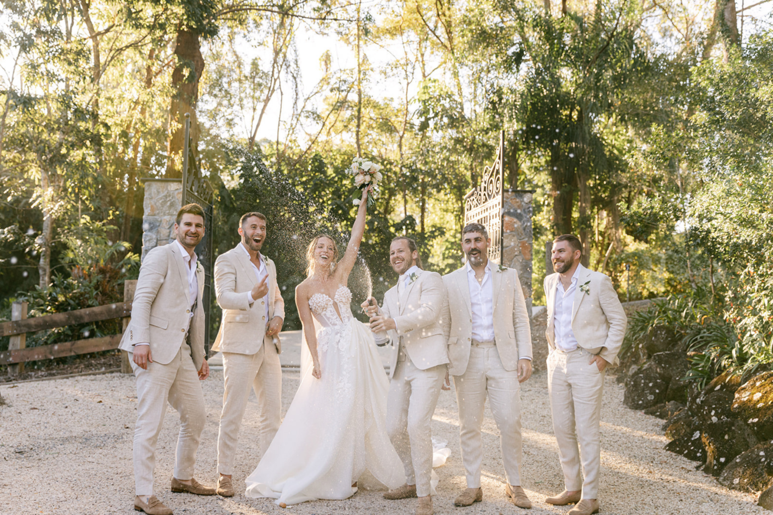 Bride and groomsmen celebrating in the garden at Kwila Lodge