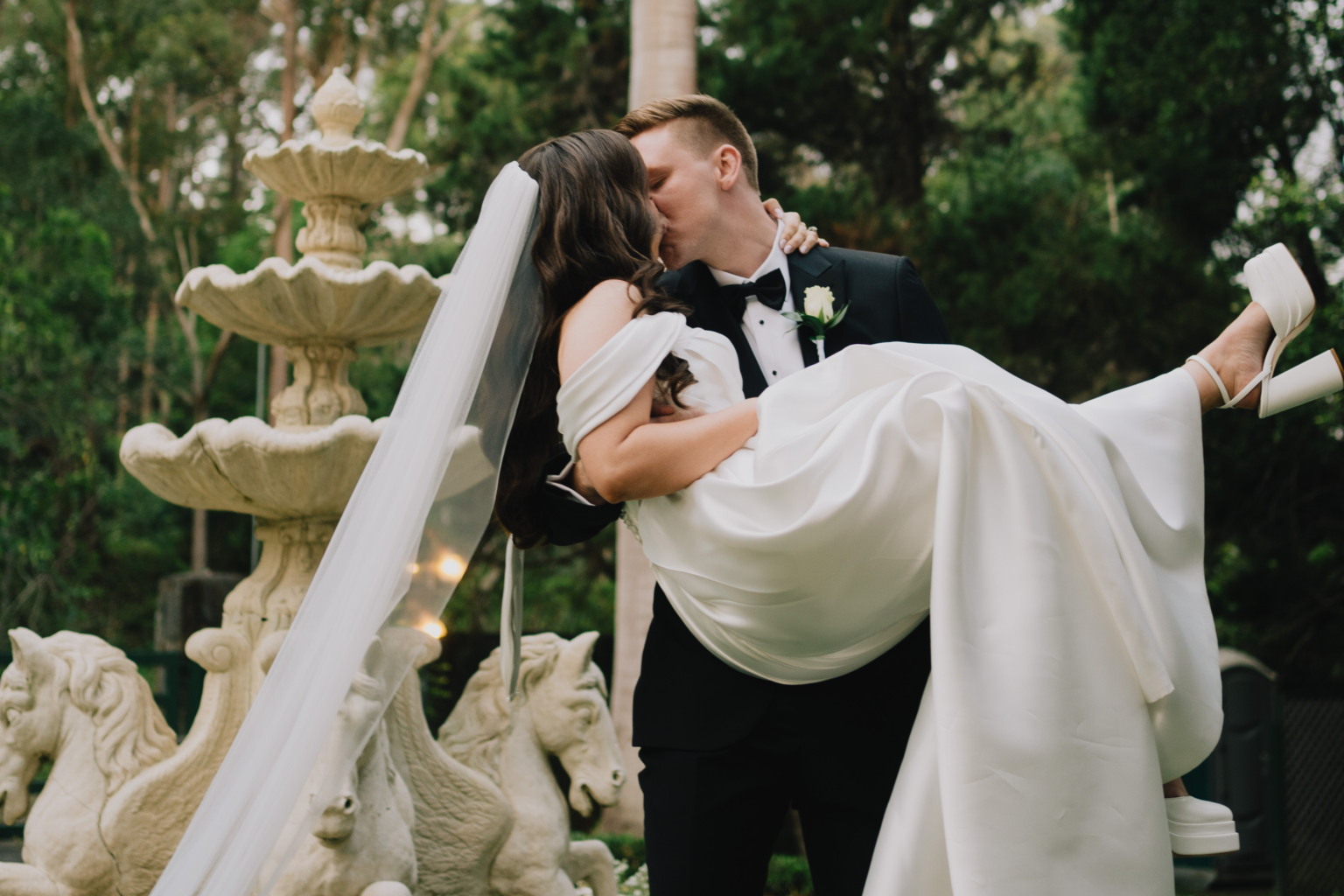 Groom carrying the bride beside the fountain