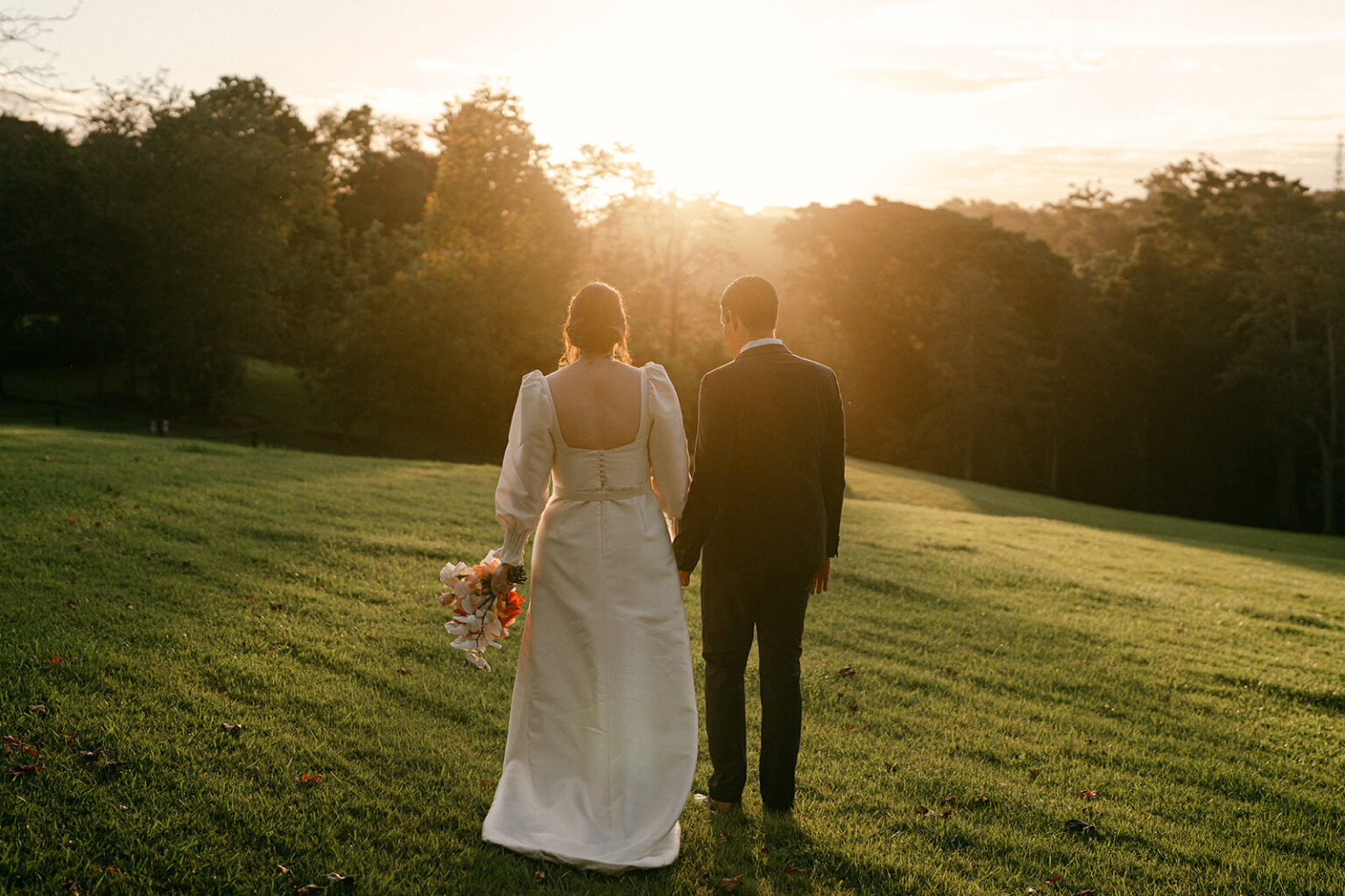 Bride and groom facing the sunset across the lawn