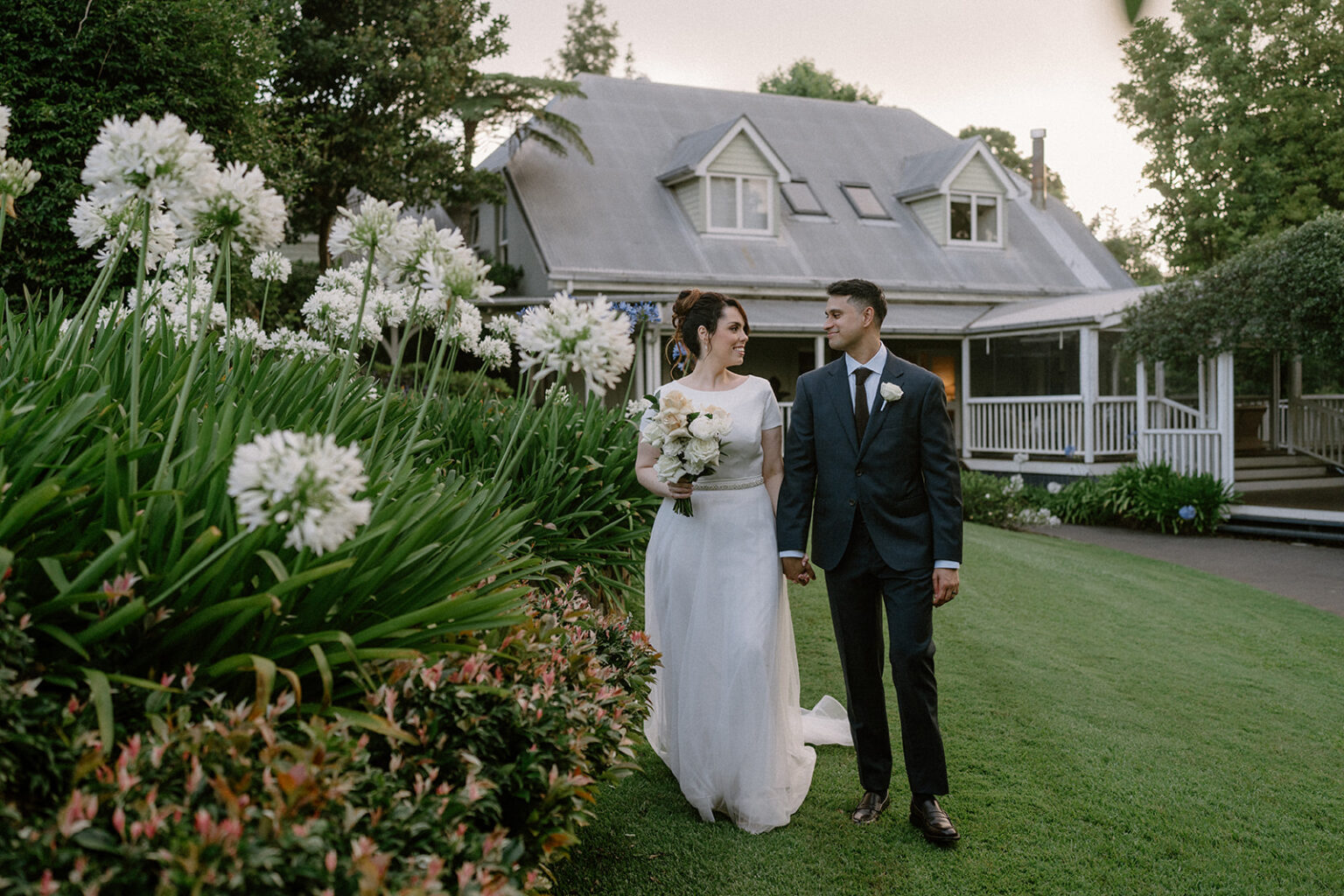 Couple among white agapanthus in front of the homestead