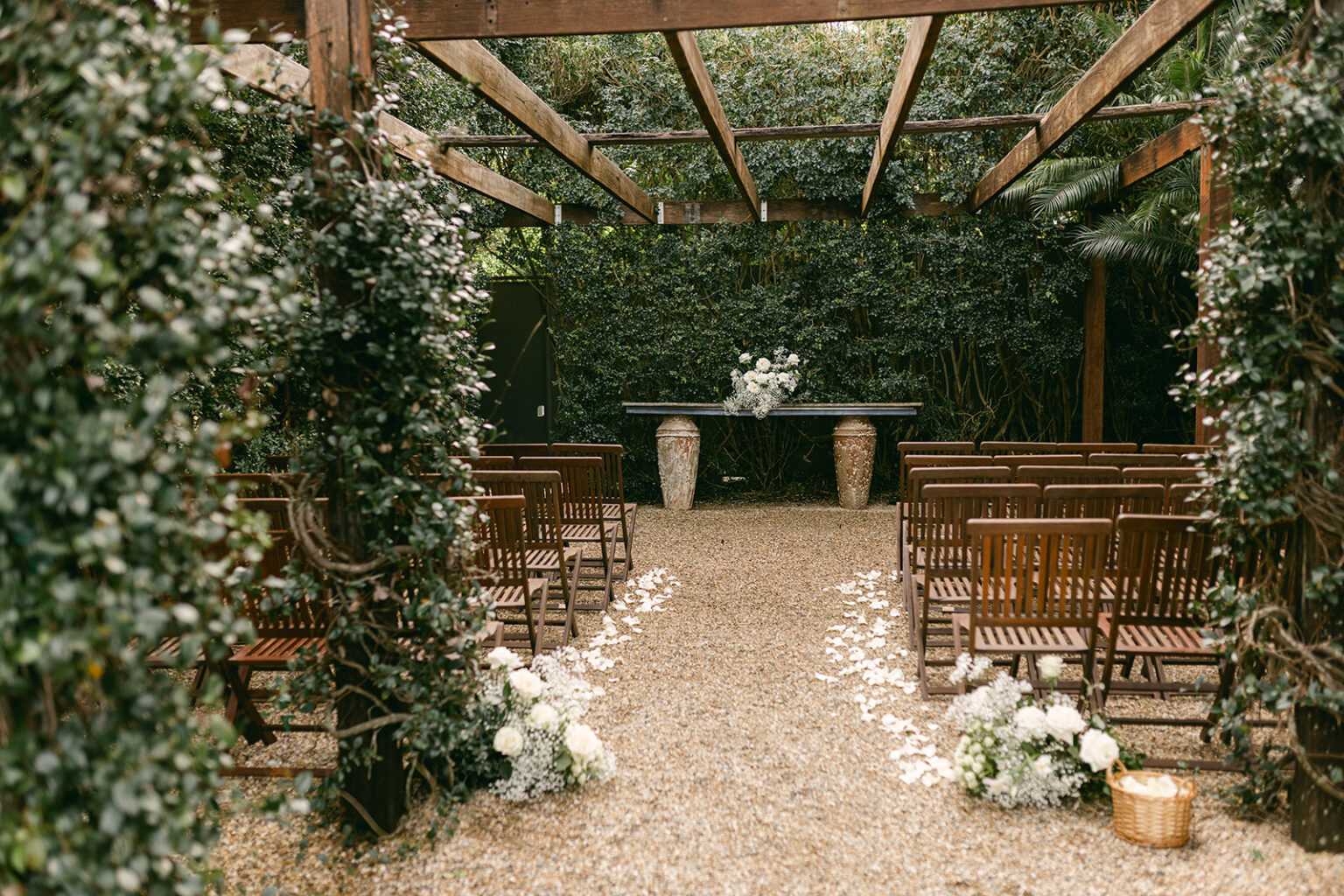 Ceremony seating beneath a vine-covered pergola