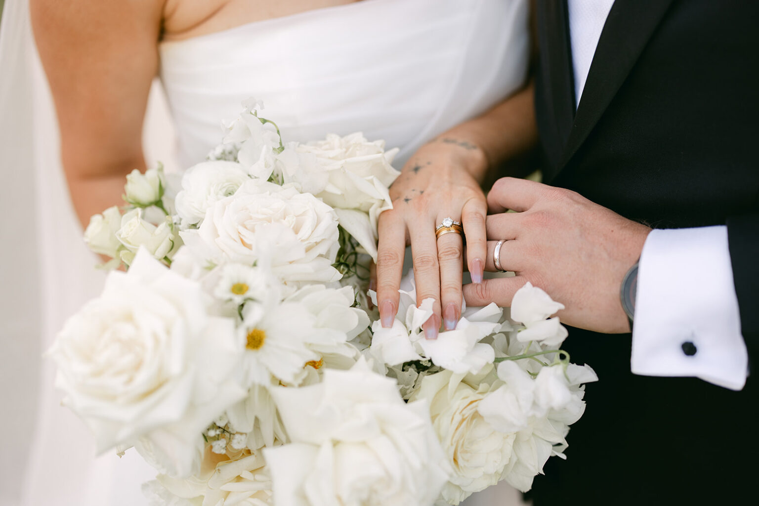 Close-up of the couple's hands and rings with a white bouquet