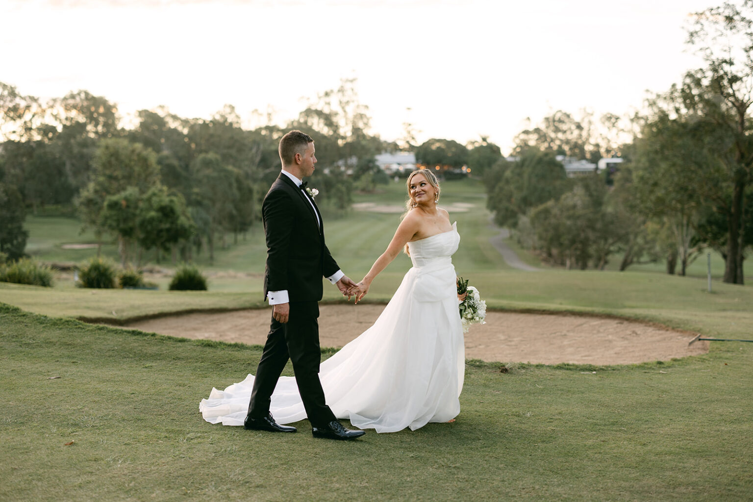 Couple walking across the golf course at sunset