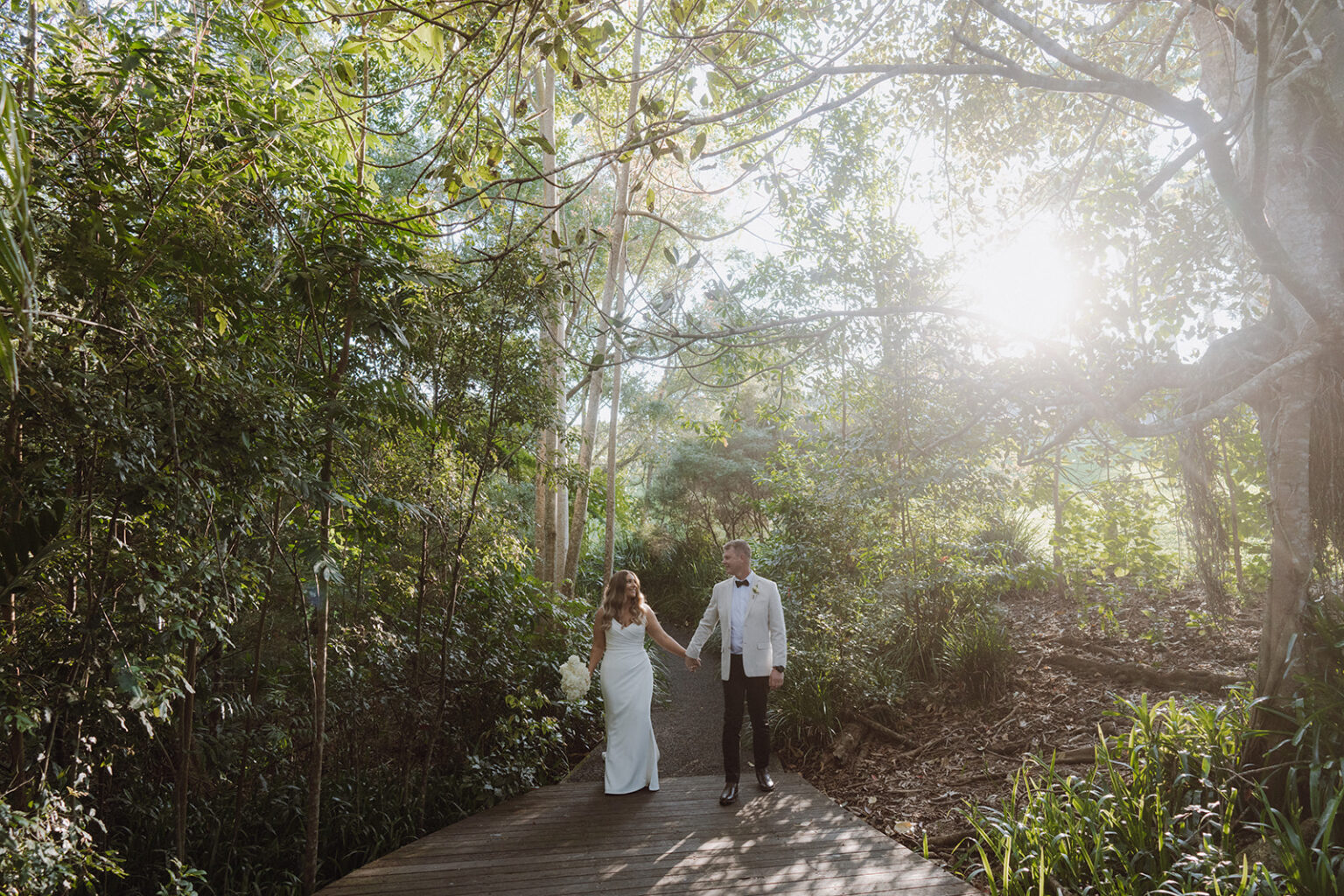 Couple walking along a sunlit rainforest boardwalk
