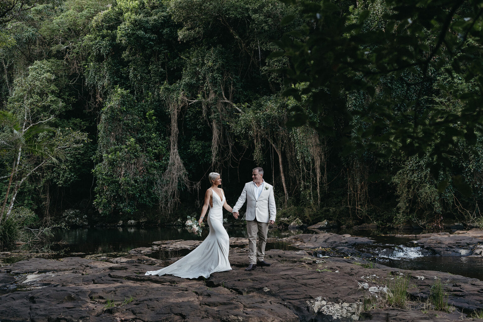 Couple walking hand in hand across the rock pools at the falls