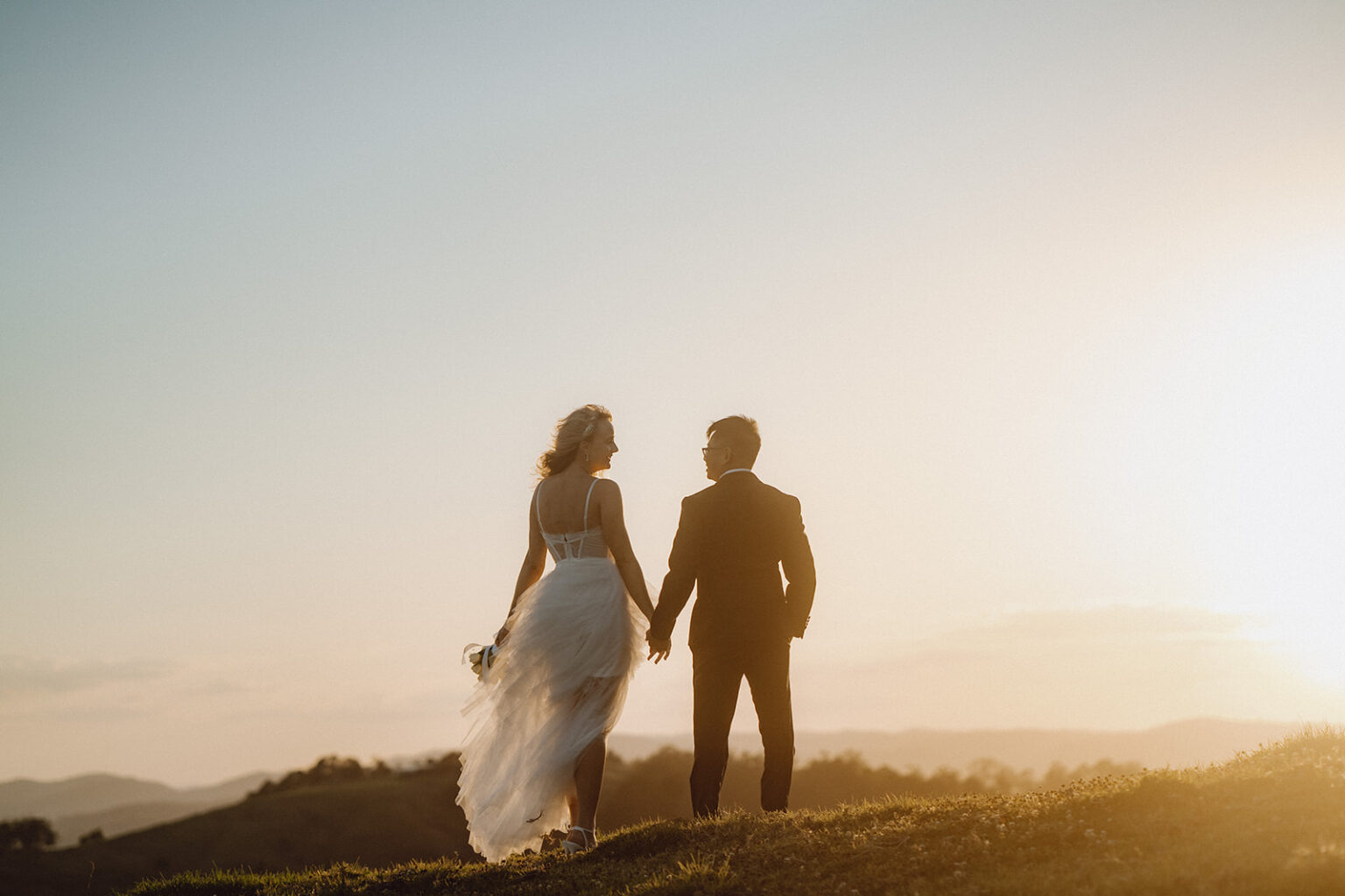 Couple silhouetted against the sunset on a ridge