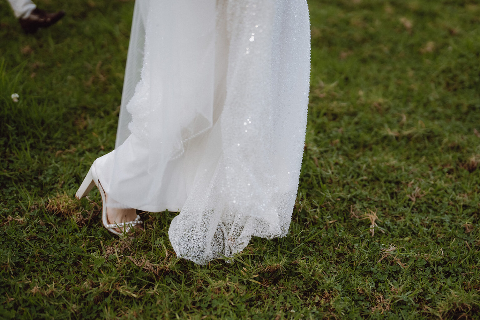 Close-up of the bride's sparkling gown on the grass