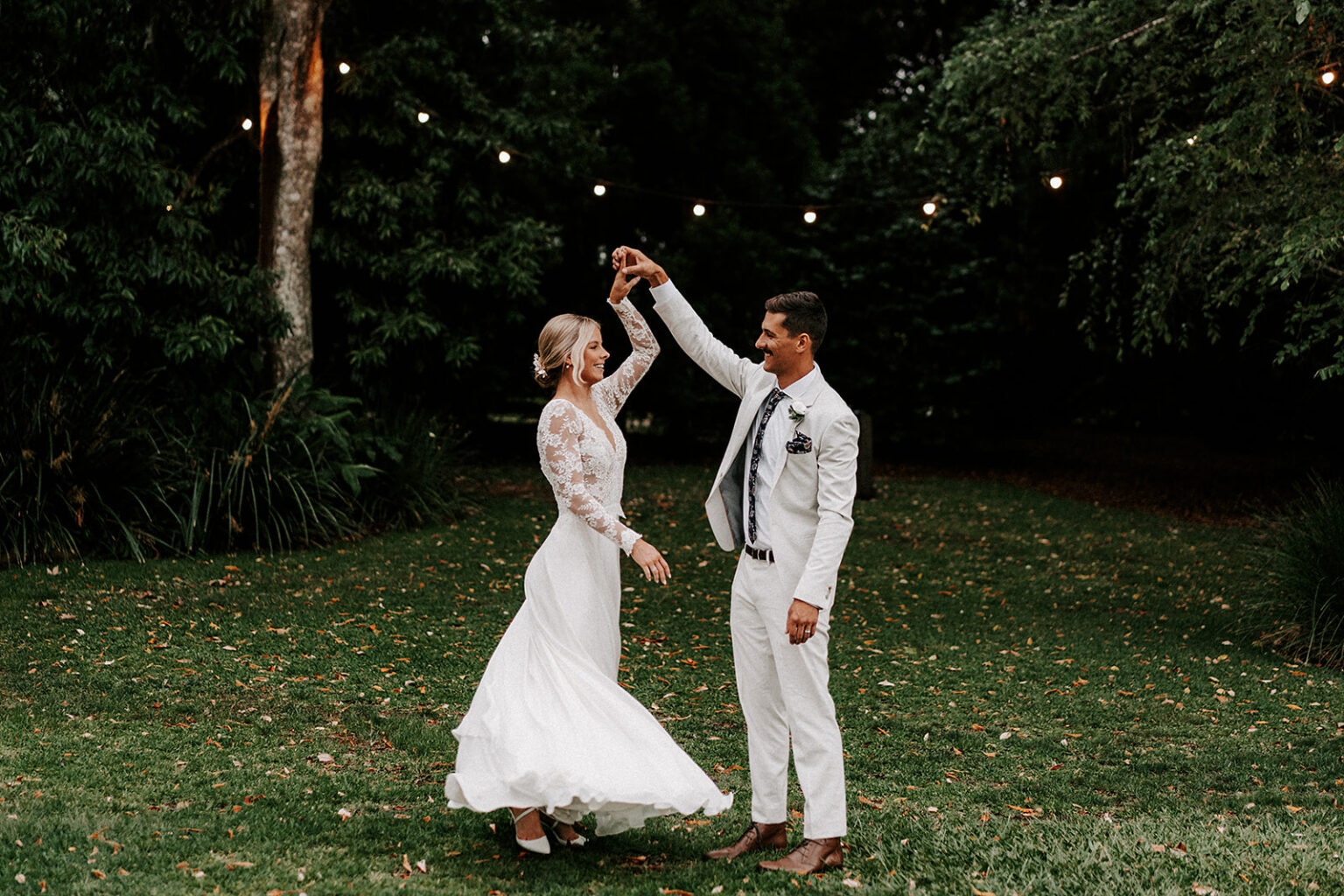 Couple dancing on the lawn under festoon lights