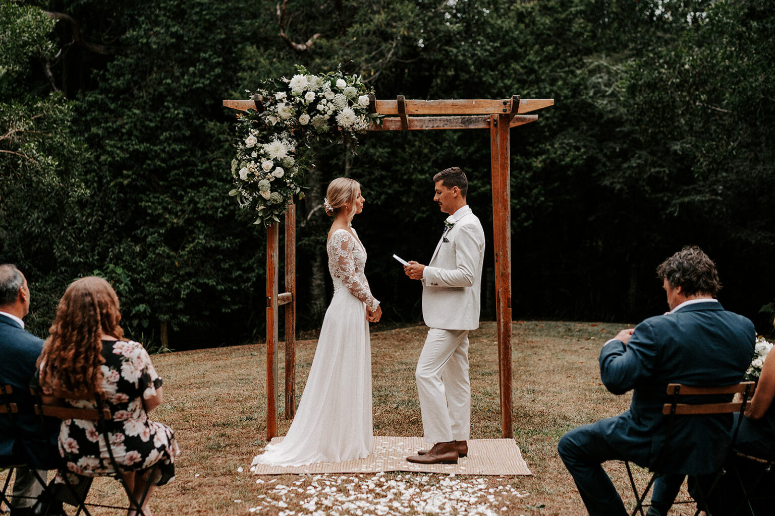 Garden ceremony beneath a floral timber arbour