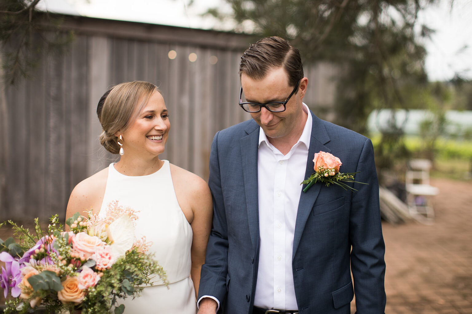 Bride and groom smiling with a bright floral bouquet