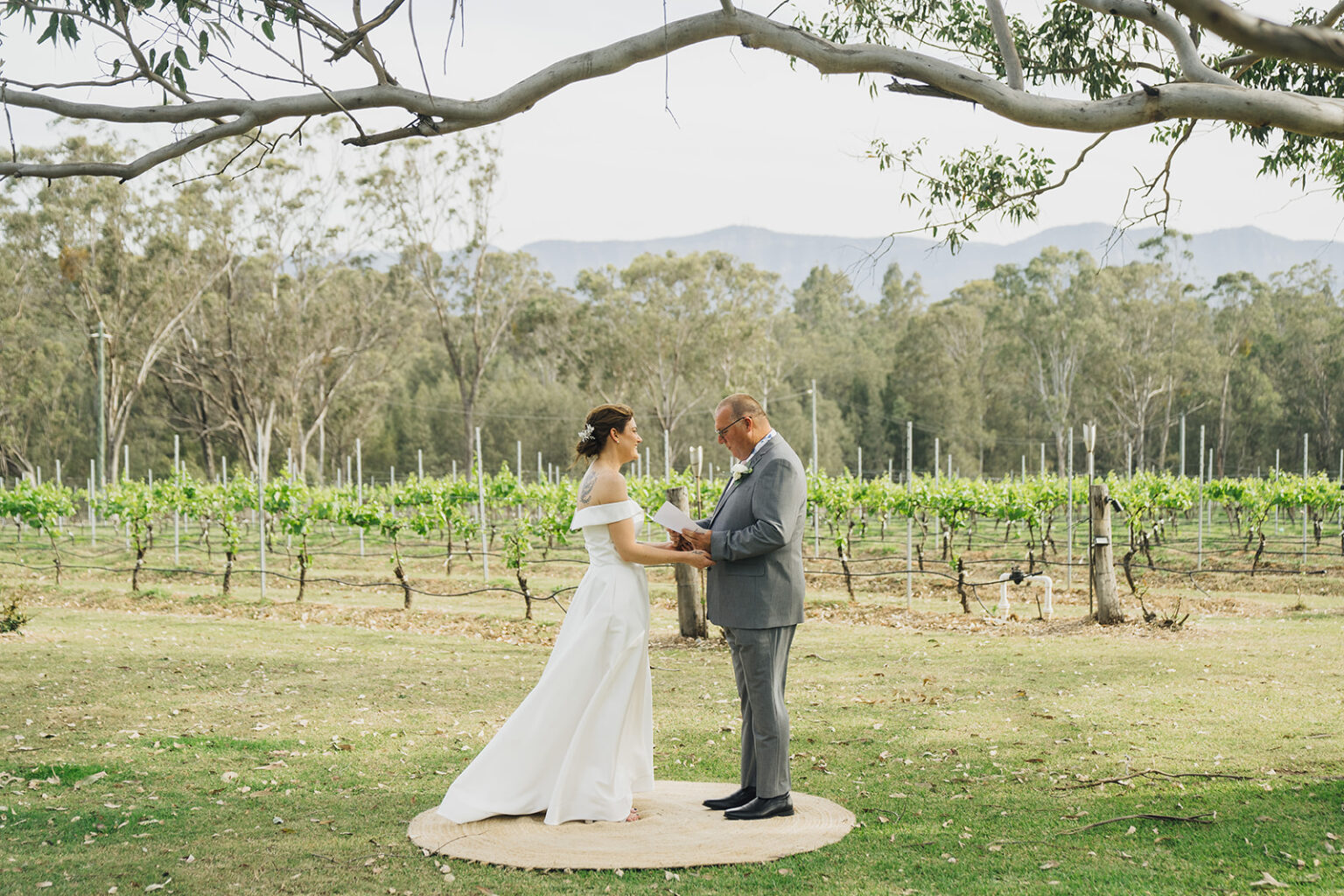 Couple exchanging vows under a gum tree with vineyard views