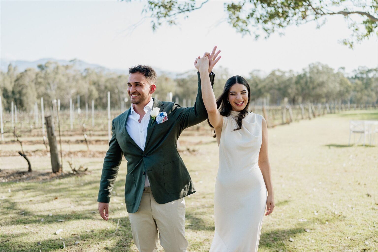 Newlyweds celebrating as they walk through the vineyard