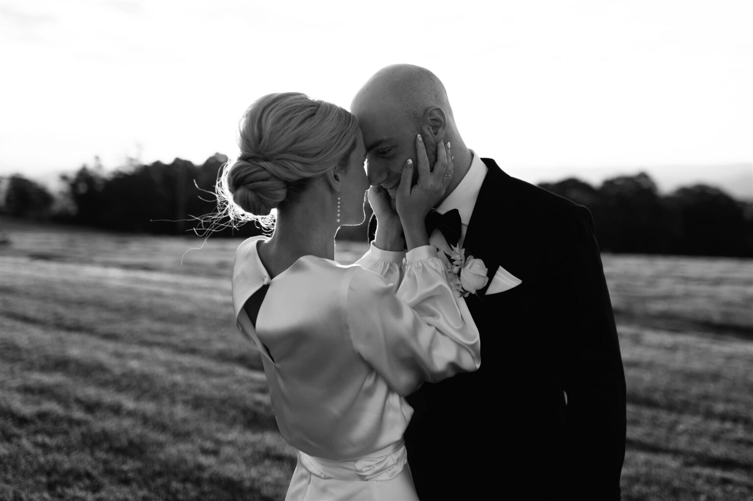 Black-and-white photo of a couple embracing in the fields
