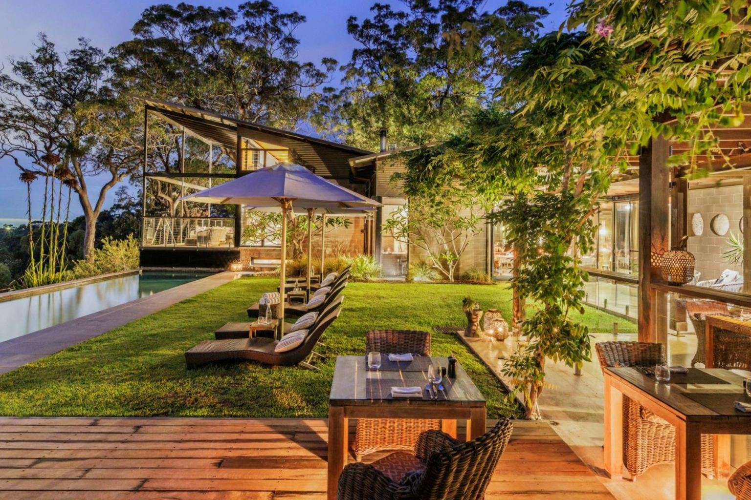 Lodge, pool and lawn lit at dusk at Spicers Sangoma Retreat