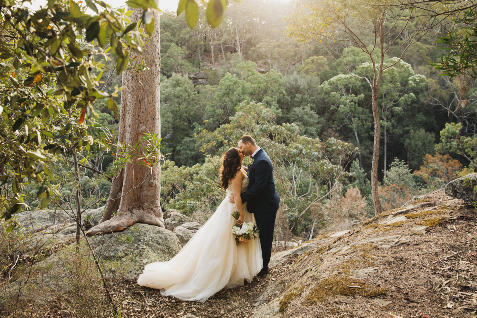 Couple kissing on a sandstone outcrop above the bushland