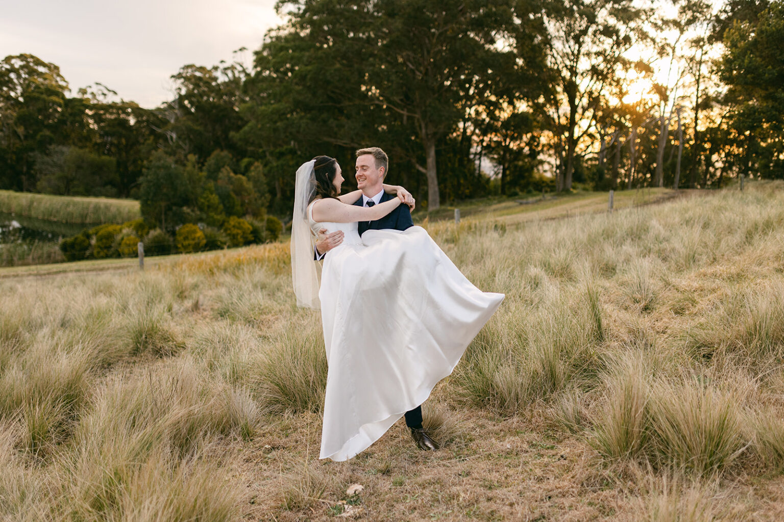 Groom lifting the bride among the tall grasses