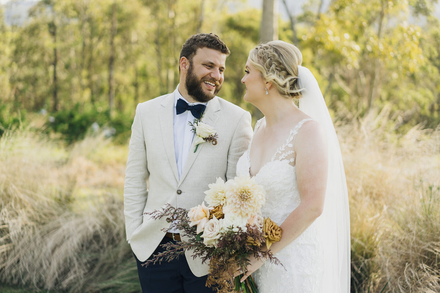Bride and groom smiling with a native bouquet