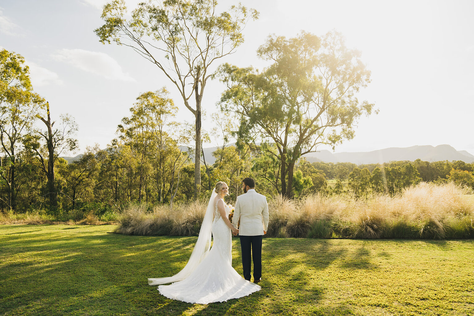 Couple embracing in the long grass at sunset