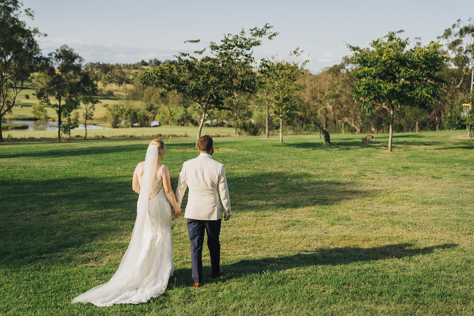 Bride and groom walking across the lawn at Spicers Guesthouse