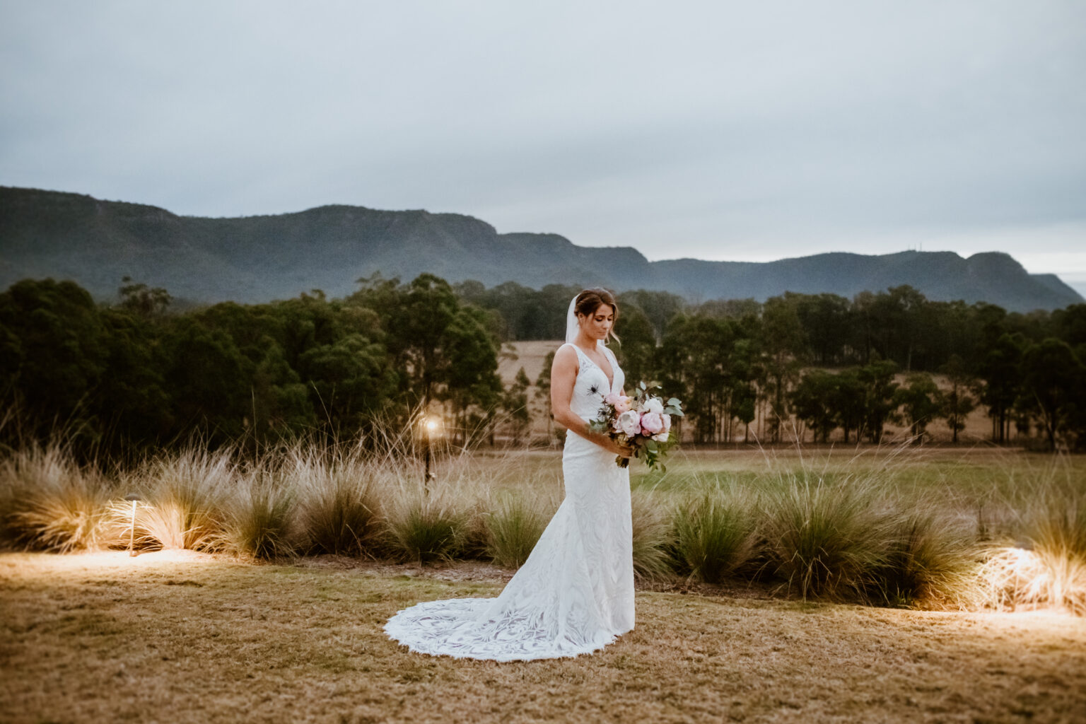 Bride on the lawn at dusk with the Brokenback Range behind