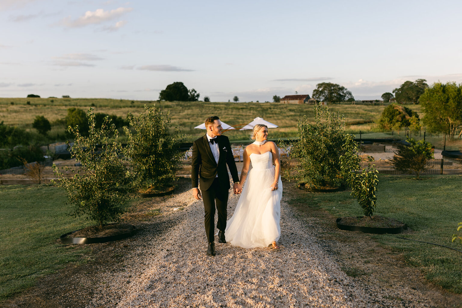 Bride and groom in cowboy hats walking along the drive at Twigley Farm