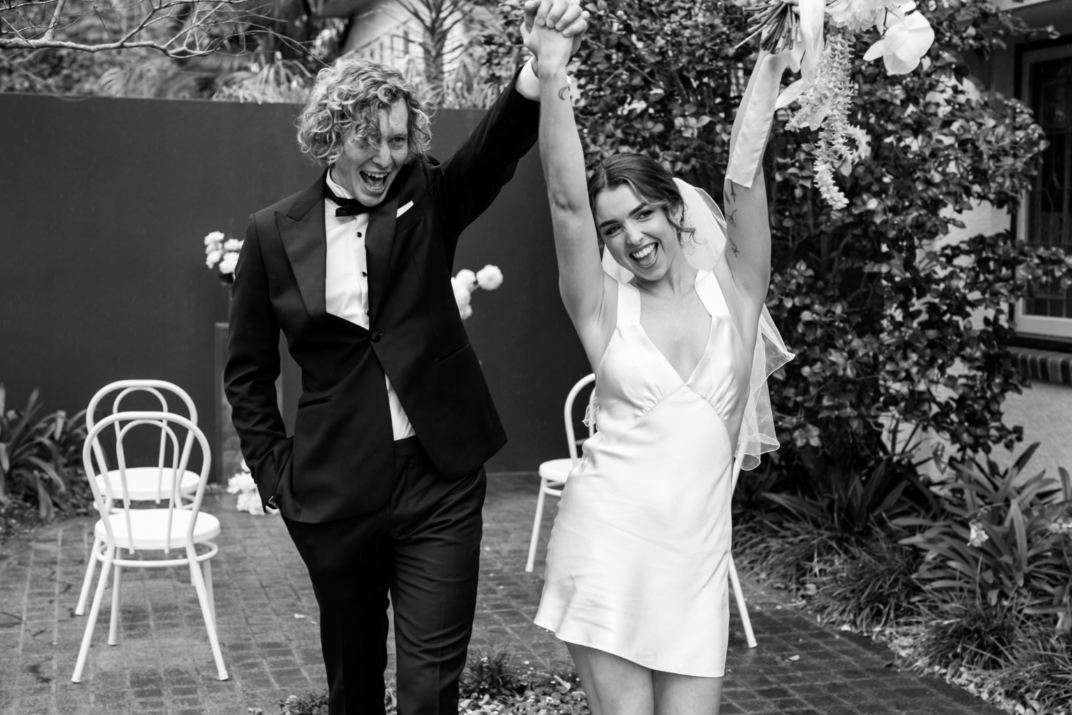 Black-and-white photo of the couple celebrating with raised hands