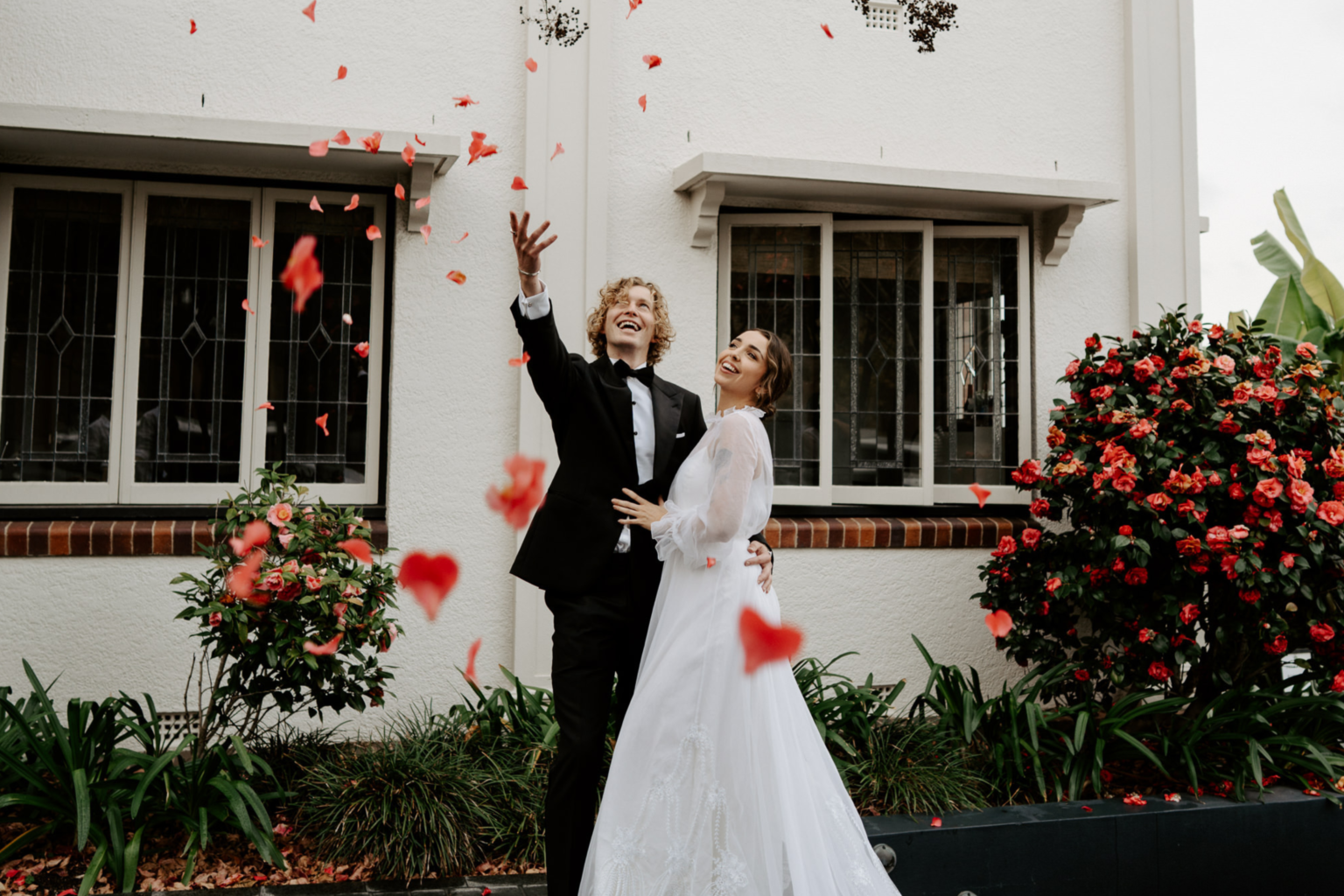Couple celebrating under falling petals outside Spicers Balfour Hotel